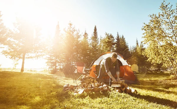 これは素晴らしいキャンプファイヤーになるでしょう 屋外でキャンプファイヤーの準備をしている青年が — ストック写真