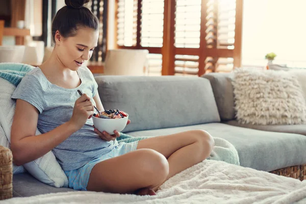 stock image This muesli is just what was needed. an attractive young woman eating her breakfast while relaxing on the sofa at home