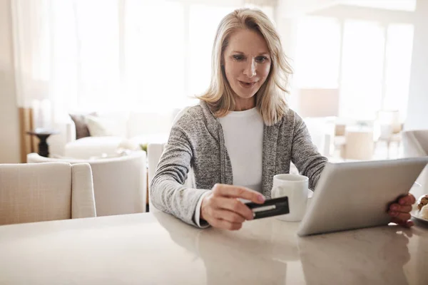 stock image What to order for dinner. a mature woman using a credit card and digital tablet while relaxing at home