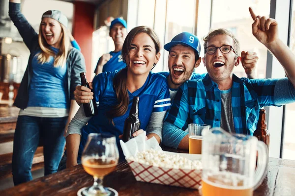 Stock image Game day is always a big event for them. a group of friends cheering while watching a sports game at a bar