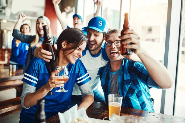 最後までチームブルー バーでスポーツの試合を見ながらビールを飲んでいる友人たちが — ストック写真
