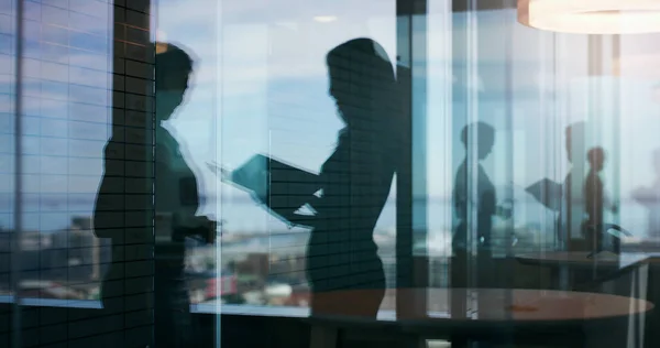 stock image Lets discuss the details. Silhouette shot of two businesspeople having a discussion inside an office building