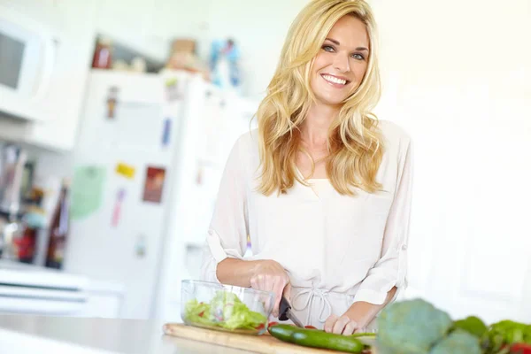 stock image Preparing a salad for dinner. Attractive young blonde woman smiling while chopping fresh vegetables at home