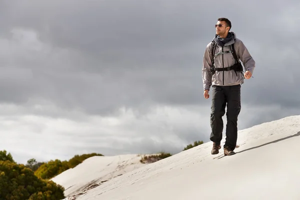 他像个老练的徒步旅行者一样管理着这些山 一个年轻的男性徒步旅行者在沙丘上行走 — 图库照片
