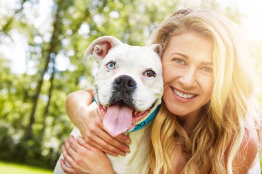 Köpekler iyi zamanları daha iyi yapar. Genç bir kadın parktaki köpeğiyle vakit geçiriyor.