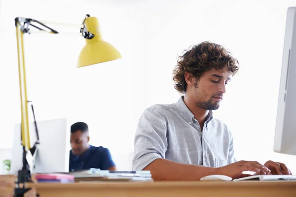 stock image Have to meet the deadline...A handsome young businessman sitting at his desk with his colleague in the background