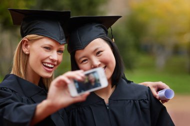 Yeni başlangıçların görüntüsü. İki üniversite mezunu selfie çekiyor.