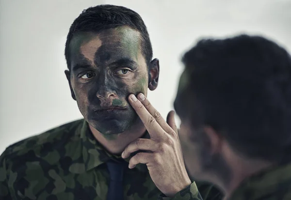 戦争の準備だ 鏡の中で彼のカモフラージュ顔を調べる若い軍隊 — ストック写真