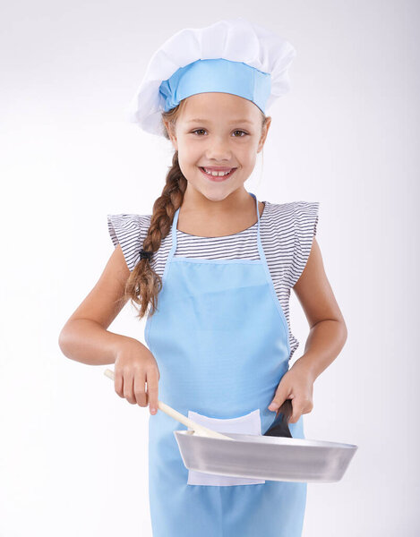 Learning how to cook. Portrait of a young girl holding a pan and wooden spoon