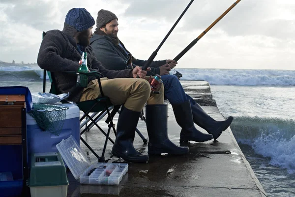 ぶら下がって魚を捕まえるだけだ 朝海で釣りをしている2人の若者が — ストック写真