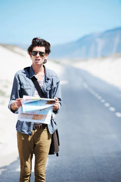 眼花缭乱迷路的年轻人站在路边 手里拿着一张地图 看上去很困惑 — 图库照片