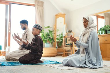 Kutsanmış. Genç bir Müslüman çift ve oğulları evdeki salonda dua ediyorlar.
