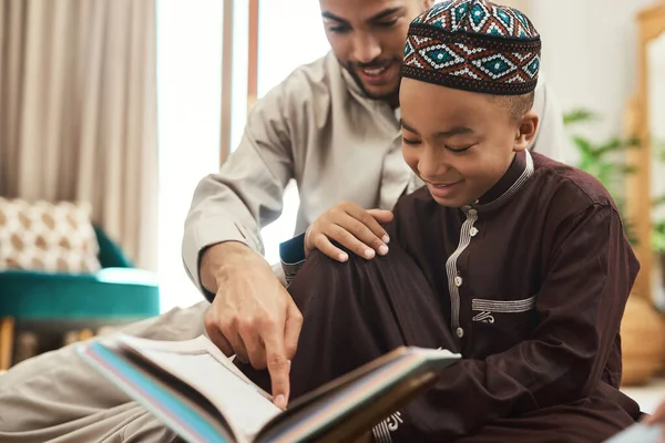 読者は死ぬ前に千人の命がある 若いイスラム教徒の男性と息子が自宅のラウンジで読書をしていて — ストック写真