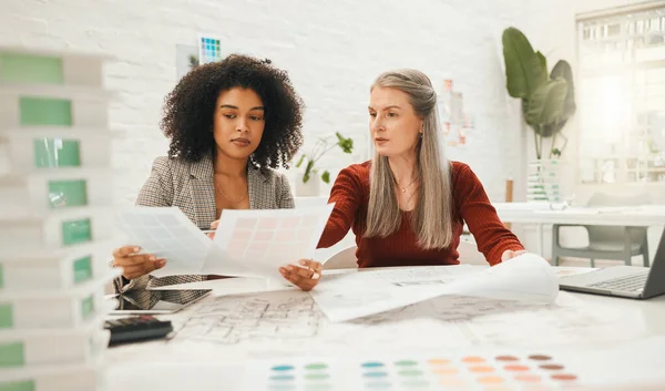 stock image Two businesspeople collaborate on a project together. Team of designers reading documents together. Mature businesswoman working with her staff member. Boss working on a architectural project.