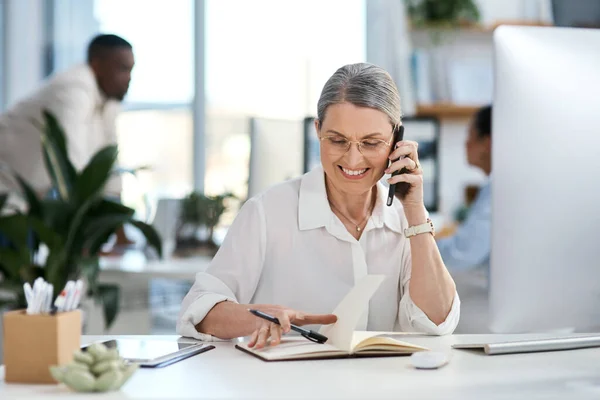 专家在做她该做的事一个成熟的女商人在办公室翻阅便条时 用手机交谈 — 图库照片