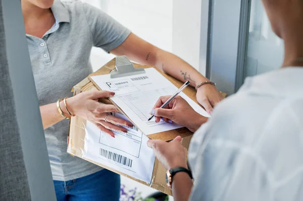 stock image Sign here, please. an unrecognizable woman standing and signing for her package from the courier