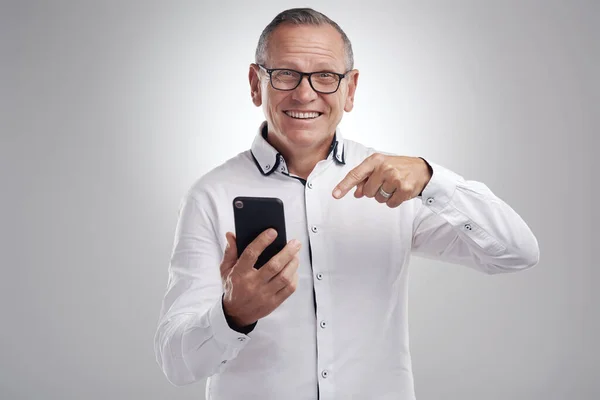 stock image You have to see what I just got. a handsome mature businessman standing alone against a grey background in the studio and using his cellphone