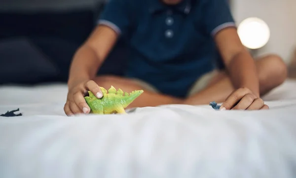 恐竜は彼の好きな動物です ベッドの上で恐竜と遊んでいるとは知らない少年が — ストック写真