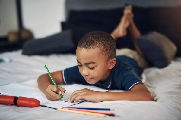 我的老师说我应该在家练习我的字母 一个在家里写字的小男孩用彩色铅笔写字 — 图库照片