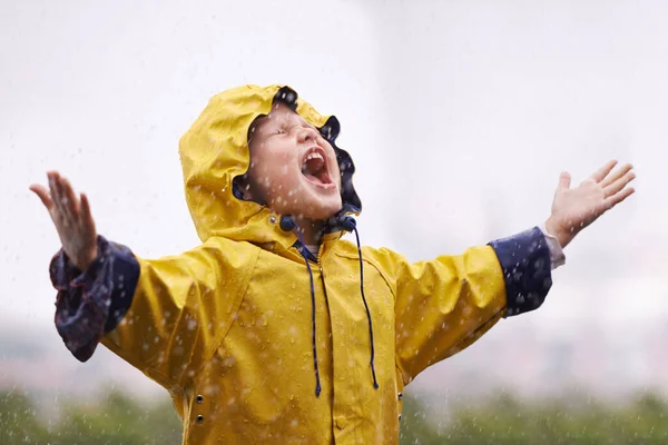Girl, playing outdoor and screaming in rain, nature and excited with winter fashion. Female child, raincoat and playful with water, open hands and happiness on adventure with freedom in childhood.