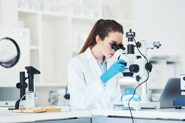 一滴で全世界だ 顕微鏡を見ている若い女性科学者が研究室内で — ストック写真