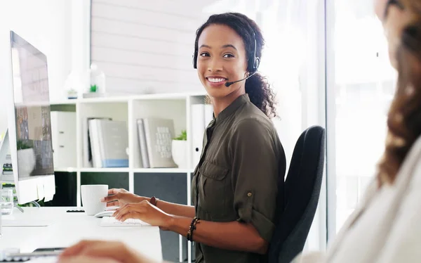创造快乐的客户一个又一个的电话 在现代化的办公室里用电脑和耳机的年轻女人 — 图库照片