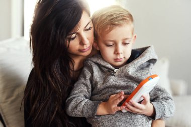 Yakında kendi cep telefonun olacak. Kaygısız genç bir kadın gün boyunca evinde bir kanepede otururken küçük oğluyla cep telefonunda geziniyor.