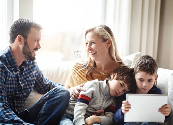 家庭时间是电影的流媒体时间 两个可爱的兄弟和他们的父母一起在家里的沙发上用数字平板电脑 — 图库照片