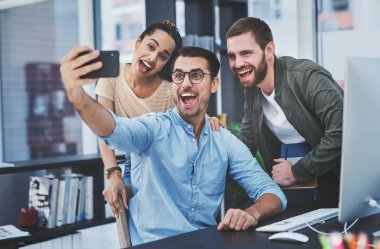 En harika takımla anılar yaratıyorum. Bir grup tasarımcı ofiste selfie çekiyor.