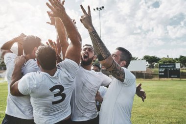 Biz en iyisiyiz. Bir grup neşeli genç rugby oyuncusu gün içindeki maçtan sonra galibiyetlerini kutluyorlar.