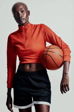 Basketbol vücuda iyi gelir. Gri arka planda basketbol oynayan çekici genç bir kadının stüdyo çekimi.