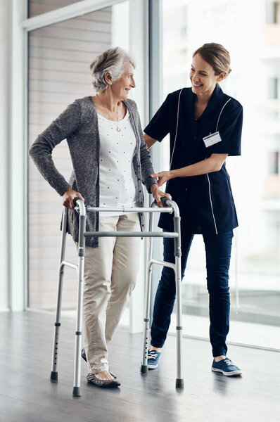 Im so proud of your progress. a female nurse assisting a senior woman using a walker