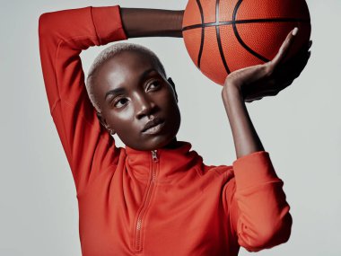 Hedefinize ulaşmak için, zihniyetinizi ayarlayın. Gri arka planda basketbol oynayan çekici genç bir kadının stüdyo çekimi.