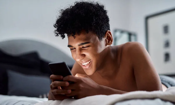 stock image A meme a day keeps the lockdown boredom away. a young man relaxing on his bed and using a smartphone