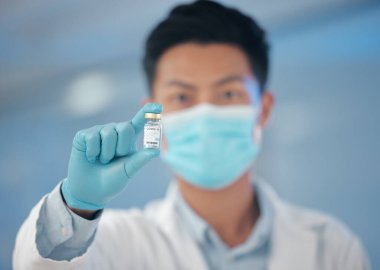 Sonunda başardılar. Genç bir erkek laboratuvar çalışanı elinde bir şişe aşı tutuyor.