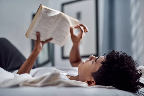 在我的世界里 一个在家里看书和在床上休息的年轻人 — 图库照片