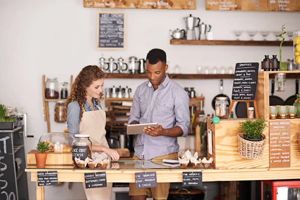 Small business owners, tablet and teamwork of people, manage orders and discussion in store. Waiters, black man and happy woman in cafe with technology for inventory, stock check and managing sales