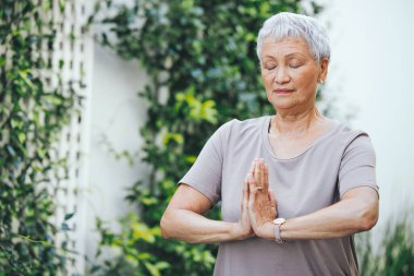 En iyilerin hayatta kalması. Dışarıda derin meditasyon yapan yaşlı bir kadın.