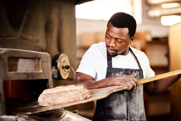 stock image Nothing taste better than bread made with love. a male baker removing freshly baked bread from the oven