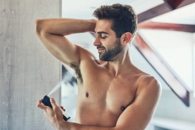 Harika koktuğun zaman harika hissedersin. Tişörtsüz neşeli bir genç adam banyodaki tek koltuk altında deodorant sıkıyor.