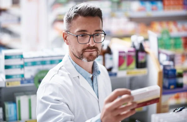 stock image Hes got your medication covered. a mature pharmacist doing inventory in a pharmacy