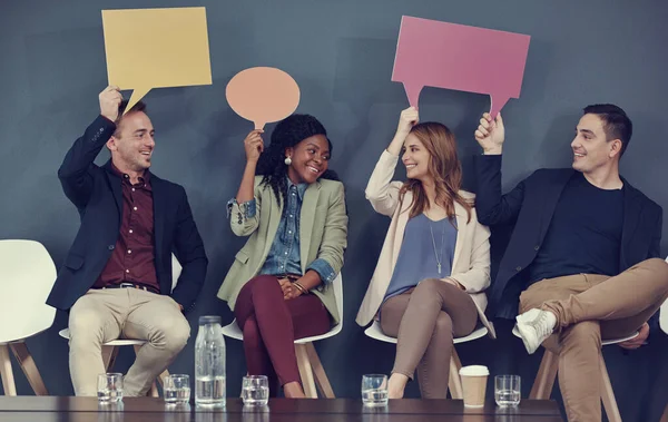 Letting their opinions be seen. a group of businesspeople holding up speech bubbles while waiting in line for an interview