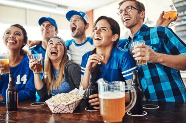 Spor hayranları en iyi yaptıkları şeyi yapıyorlar. Bir grup arkadaş barda maç izlerken bira içiyorlar.