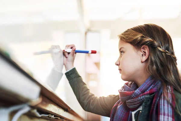 stock image Shes teaching the whole class a lesson today. an elementary school girl writing on a whiteboard in class