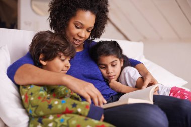 Anne, çocuklar ve bir aile evinde masal zamanı için bir kanepede gülümseyen bir kitap okumak. Çocuklu bir kadın ya da anne bir fantezi ya da peri masalı ile birlikte öğrenme, öğrenme ve sevme.