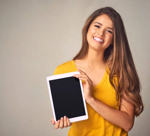 stock image Give your device a lease of new life. an attractive young woman holding a digital tablet with a blank screen against a grey background