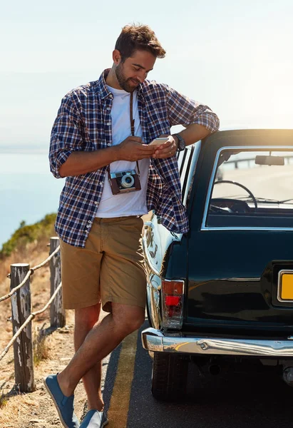 stock image Im about halfway there. Full length shot of a handsome man sending a text while enjoying a roadtrip