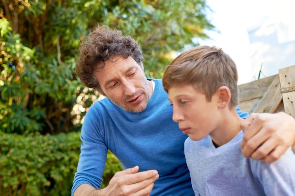 stock image Family, father talking with son in backyard, bonding with love and care, communication and relationship. Man with sad teen boy, help with advice at home and outdoor together with trust and support.