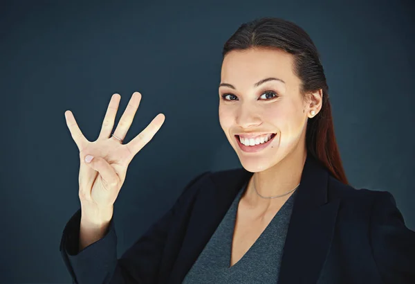 Guess how many times Ive won businesswoman of the year. Portrait of a young businesswoman showing a number with her fingers against a dark background