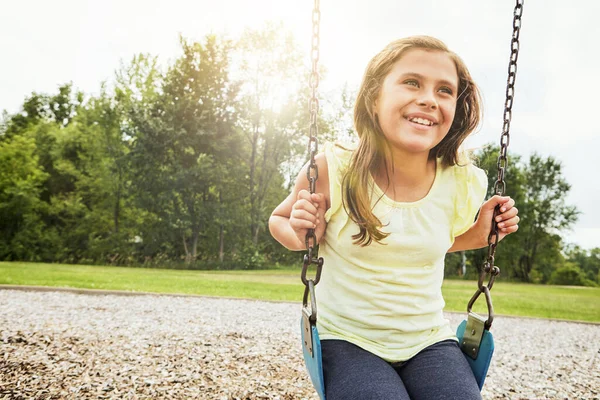 stock image Swinging the day away. a young girl playing on a swing at the park